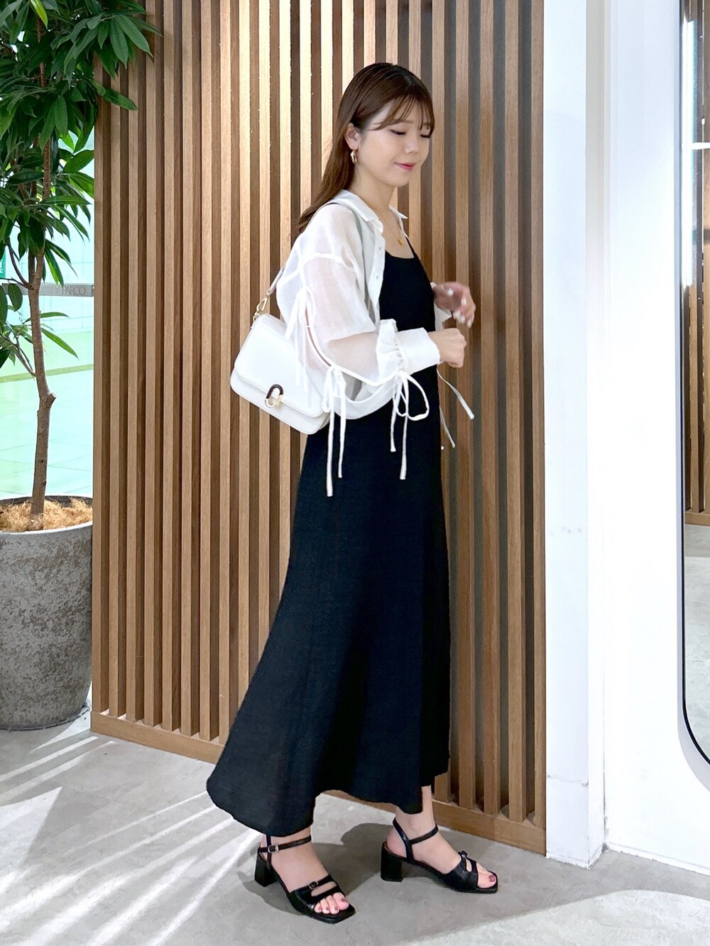 ブラック系のワンピース、ホワイト系のショルダーバッグ、ブラック系のキャミソールを着用したレディースの夏コーディネートの3枚目の写真