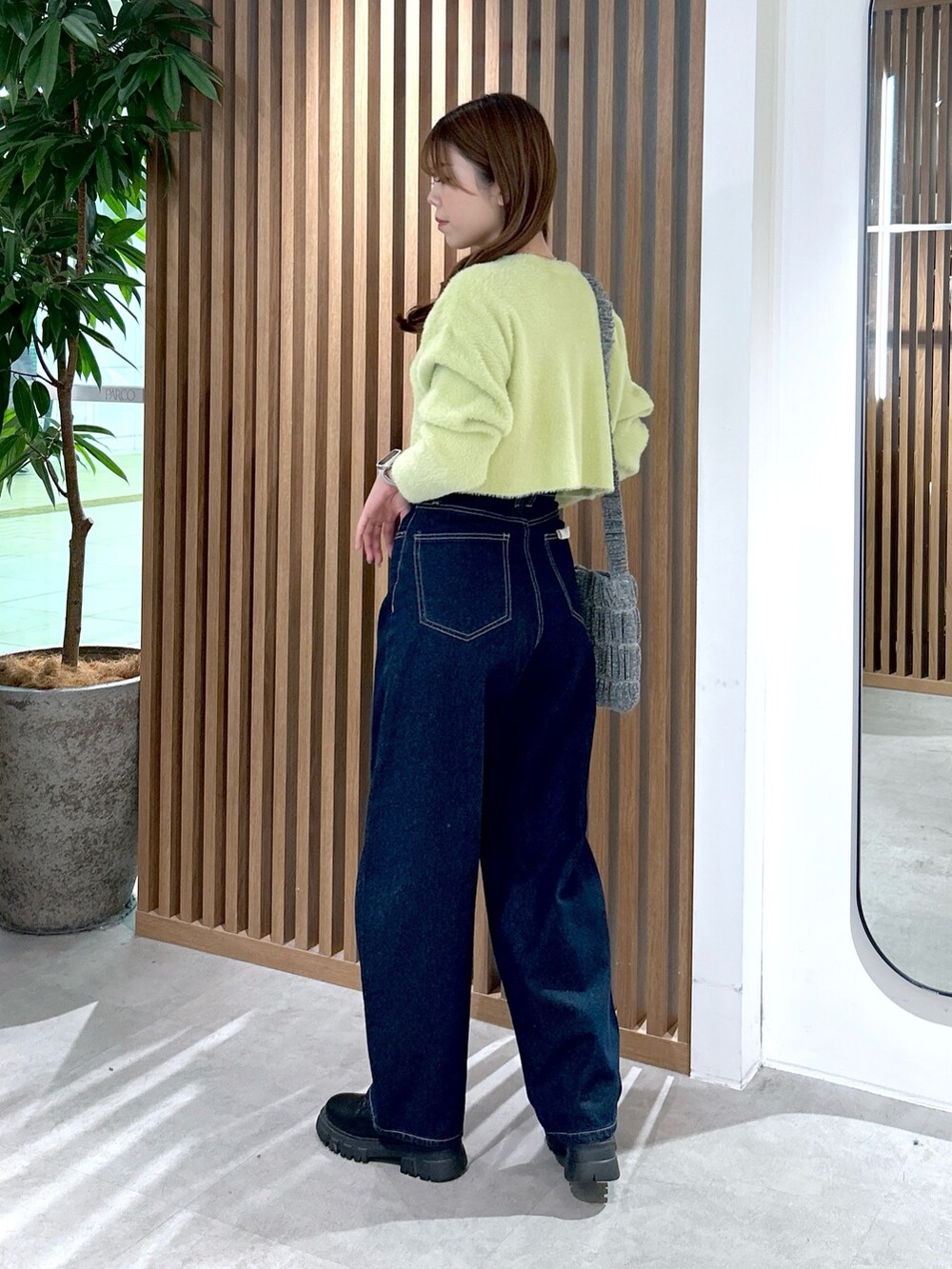 グリーン系のカーディガン/ボレロ、シルバー系のショルダーバッグ、ブルー系のデニムパンツを着用したレディースの冬コーディネートの3枚目の写真