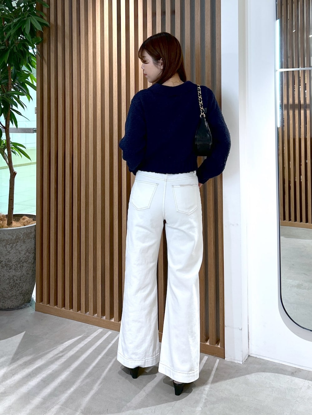 ブルー系のカーディガン/ボレロ、ブラック系のトートバッグ、ホワイト系のデニムパンツを着用したレディースの冬コーディネートの4枚目の写真