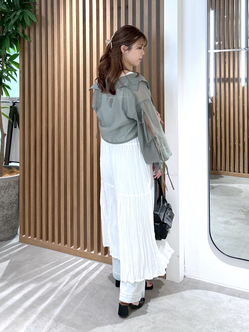 ホワイト系のワンピース、ブラック系のキャミソール、ブラック系のハンドバッグを着用したレディースの夏コーディネートの3枚目の写真