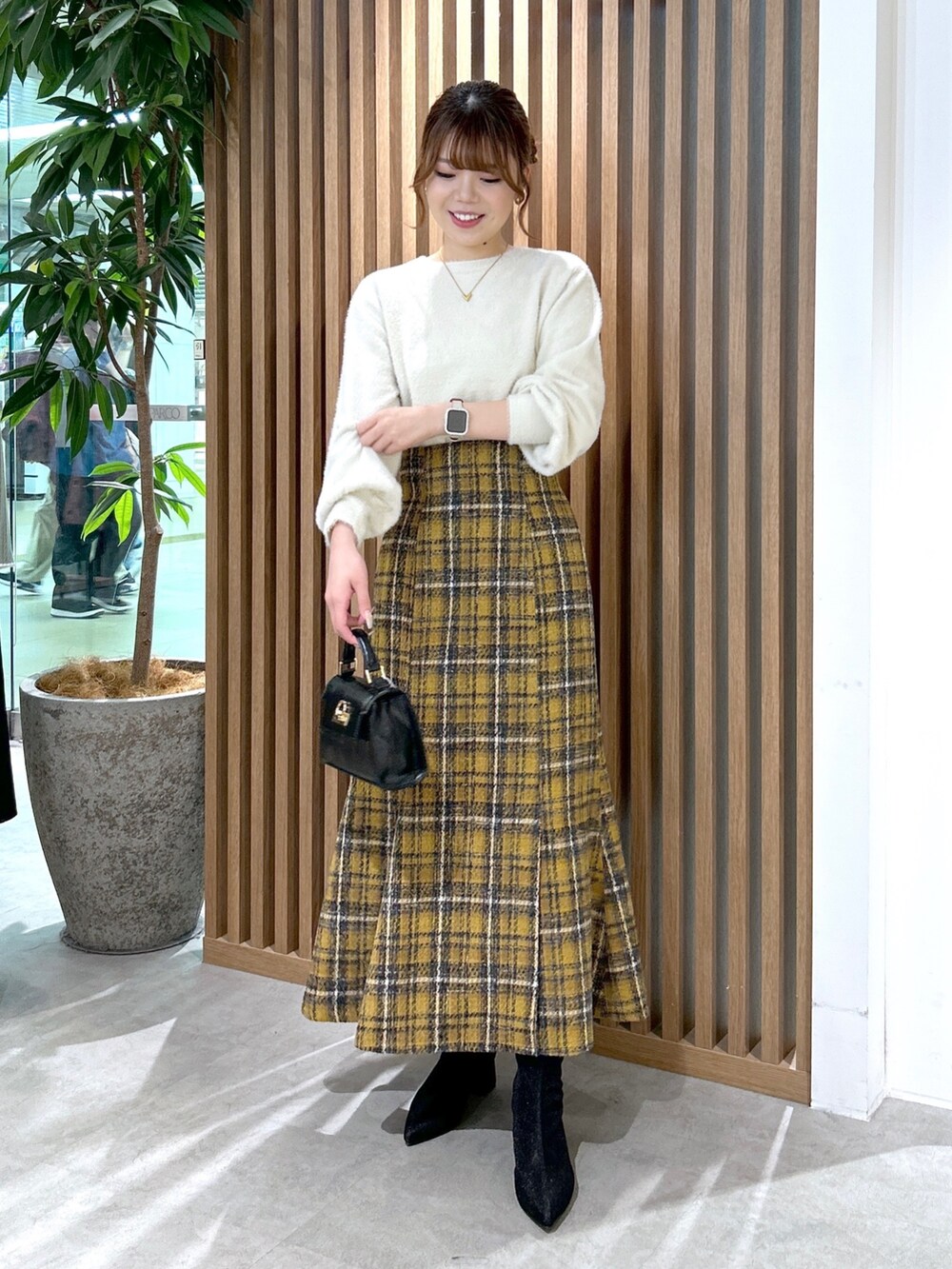 ホワイト系のニット/セーター、イエロー系のスカート、ブラック系のショルダーバッグを着用したレディースの秋コーディネートの2枚目の写真