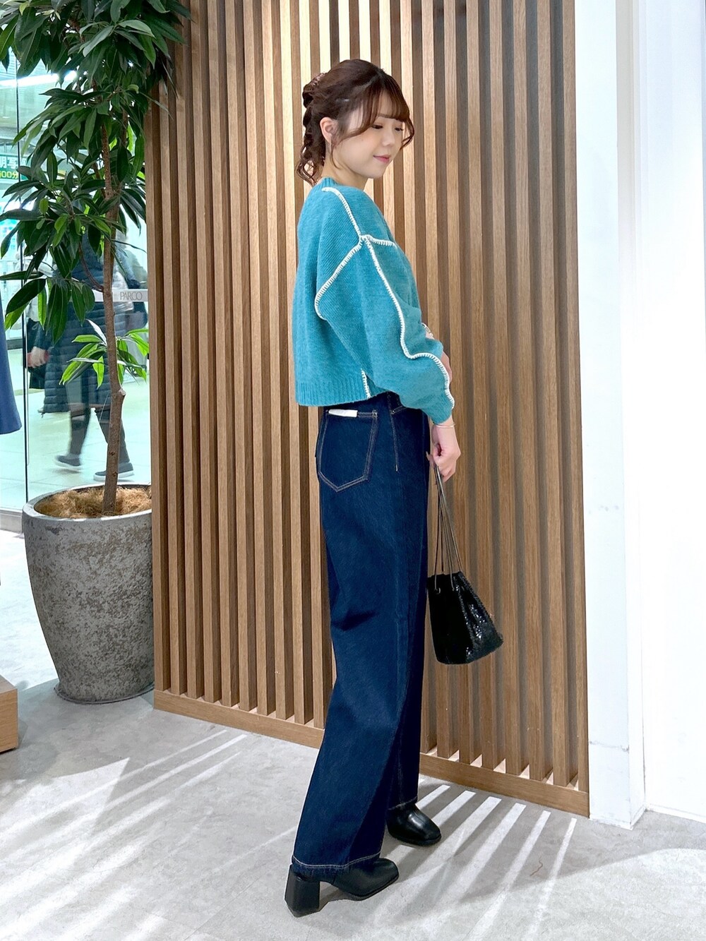 グリーン系のニット/セーター、ブルー系のデニムパンツ、ブラック系のショルダーバッグを着用したレディースの冬コーディネートの2枚目の写真