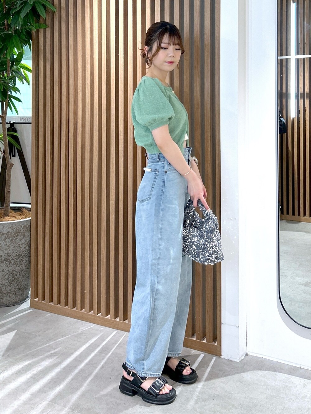 グリーン系のカーディガン/ボレロ、ホワイト系のキャミソール、ブルー系のデニムパンツを着用したレディースの春コーディネートの3枚目の写真