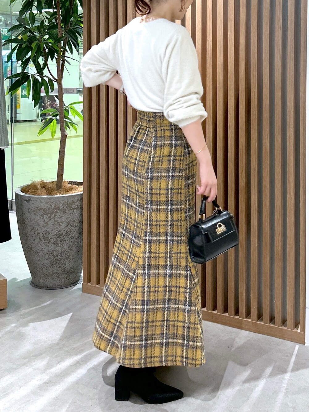ホワイト系のニット/セーター、イエロー系のスカート、ブラック系のショルダーバッグを着用したレディースの秋コーディネートの3枚目の写真