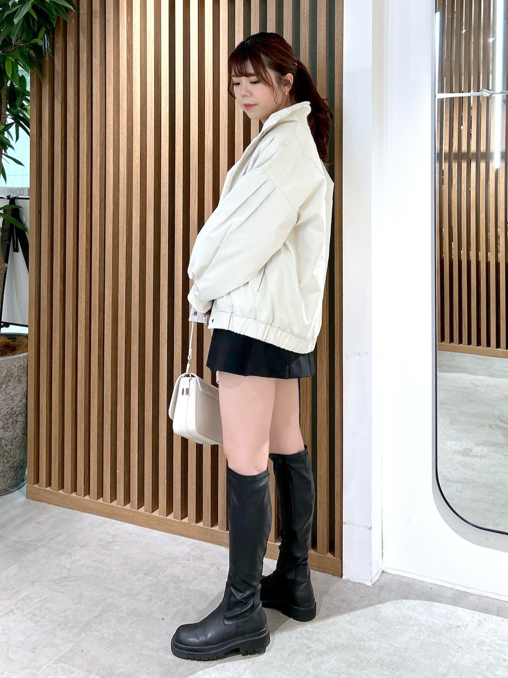 ホワイト系のブルゾン、ベージュ系のTシャツ/カットソー、ホワイト系のショルダーバッグを着用したレディースの冬コーディネートの3枚目の写真