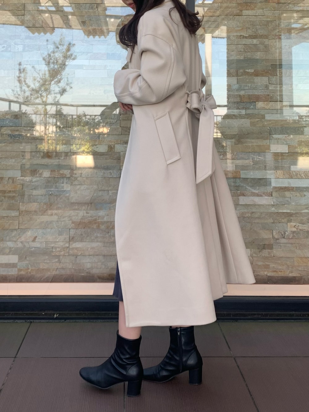 ブラック系のワンピース、ベージュ系のステンカラーコート、ブラック系のベルトを着用したレディースの秋コーディネートの2枚目の写真