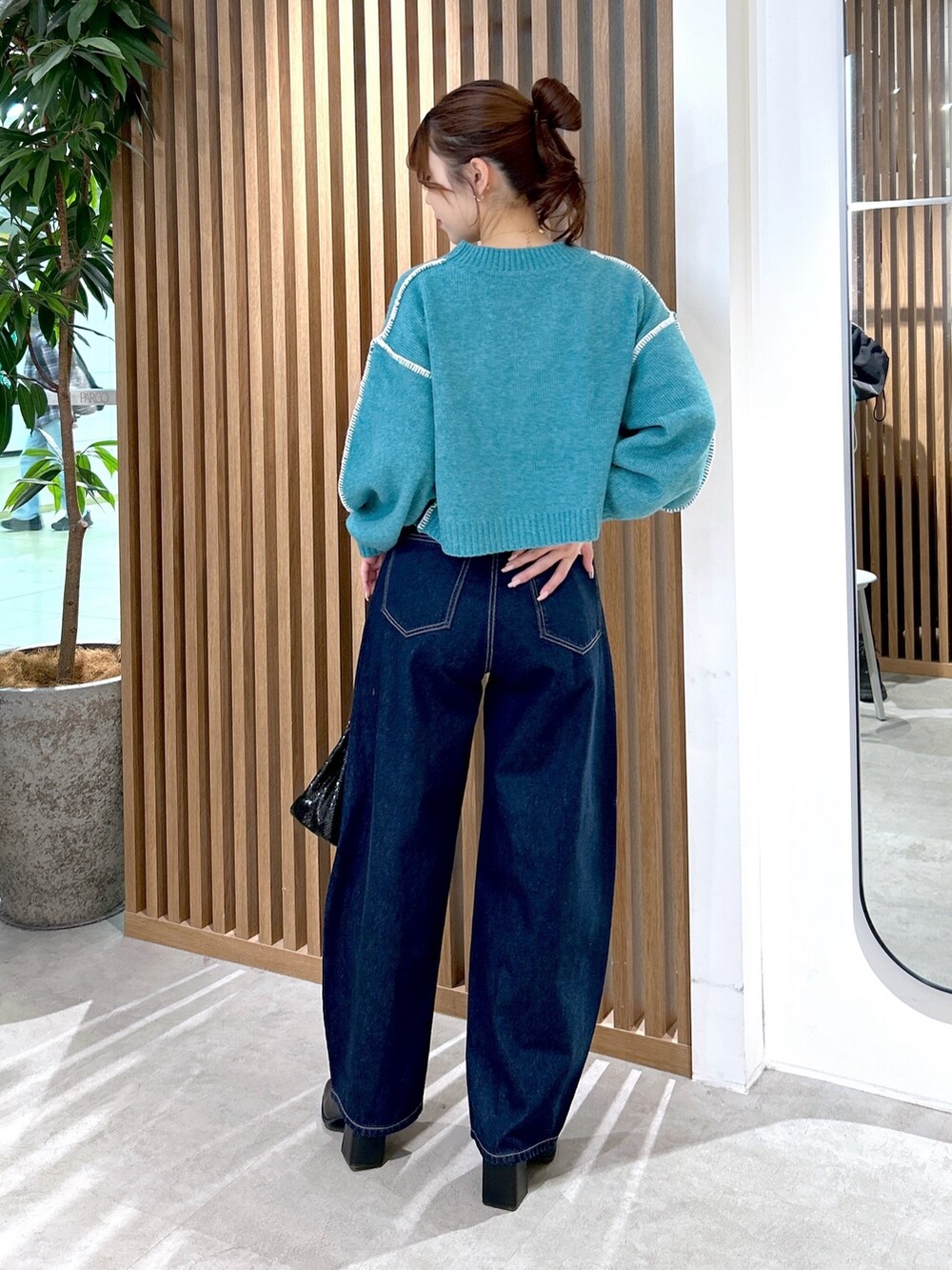 グリーン系のニット/セーター、ブルー系のデニムパンツ、ブラック系のショルダーバッグを着用したレディースの冬コーディネートの4枚目の写真