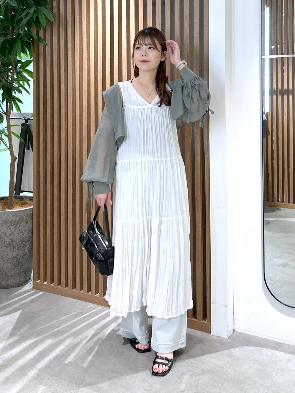 ホワイト系のワンピース、ブラック系のキャミソール、ブラック系のハンドバッグを着用したレディースの夏コーディネートの2枚目の写真