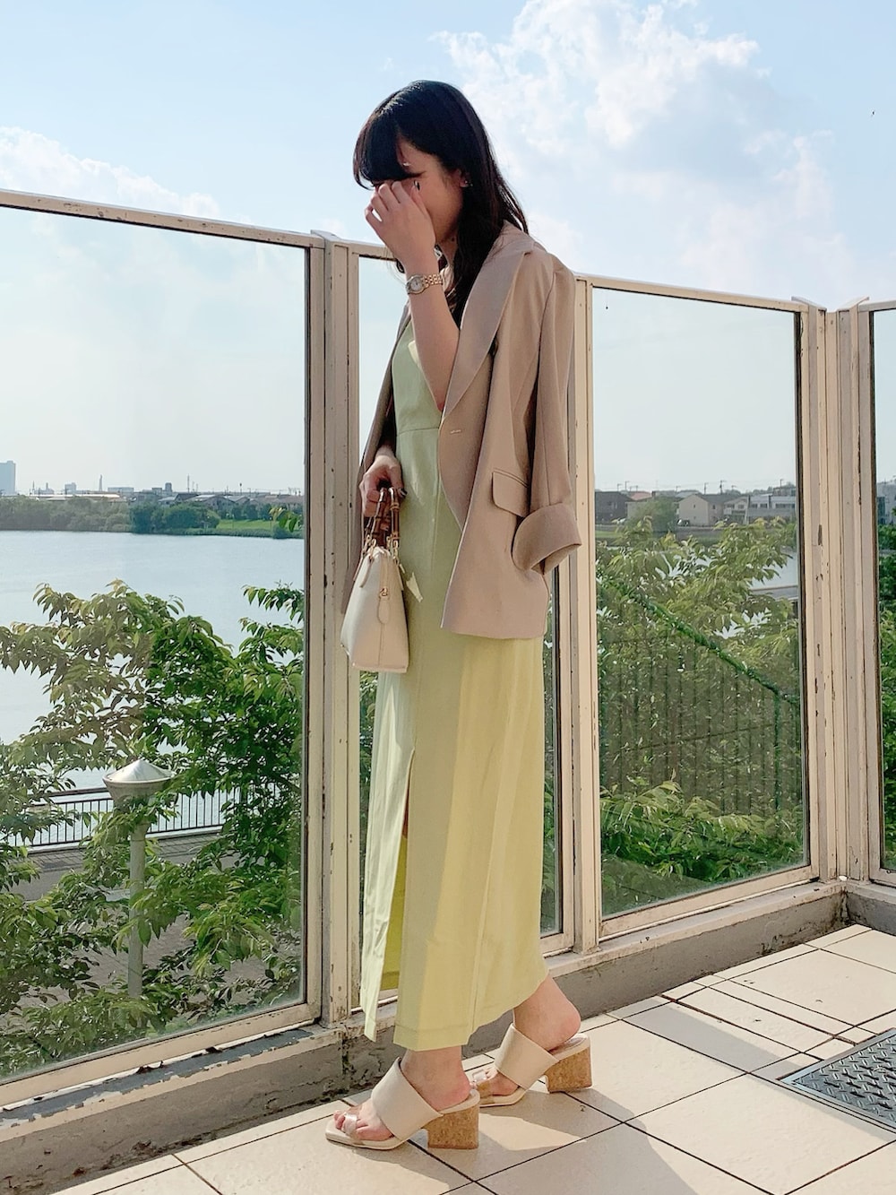 ベージュ系のテーラードジャケット、ホワイト系のショルダーバッグ、イエロー系のワンピースを着用したレディースの春コーディネートの2枚目の写真