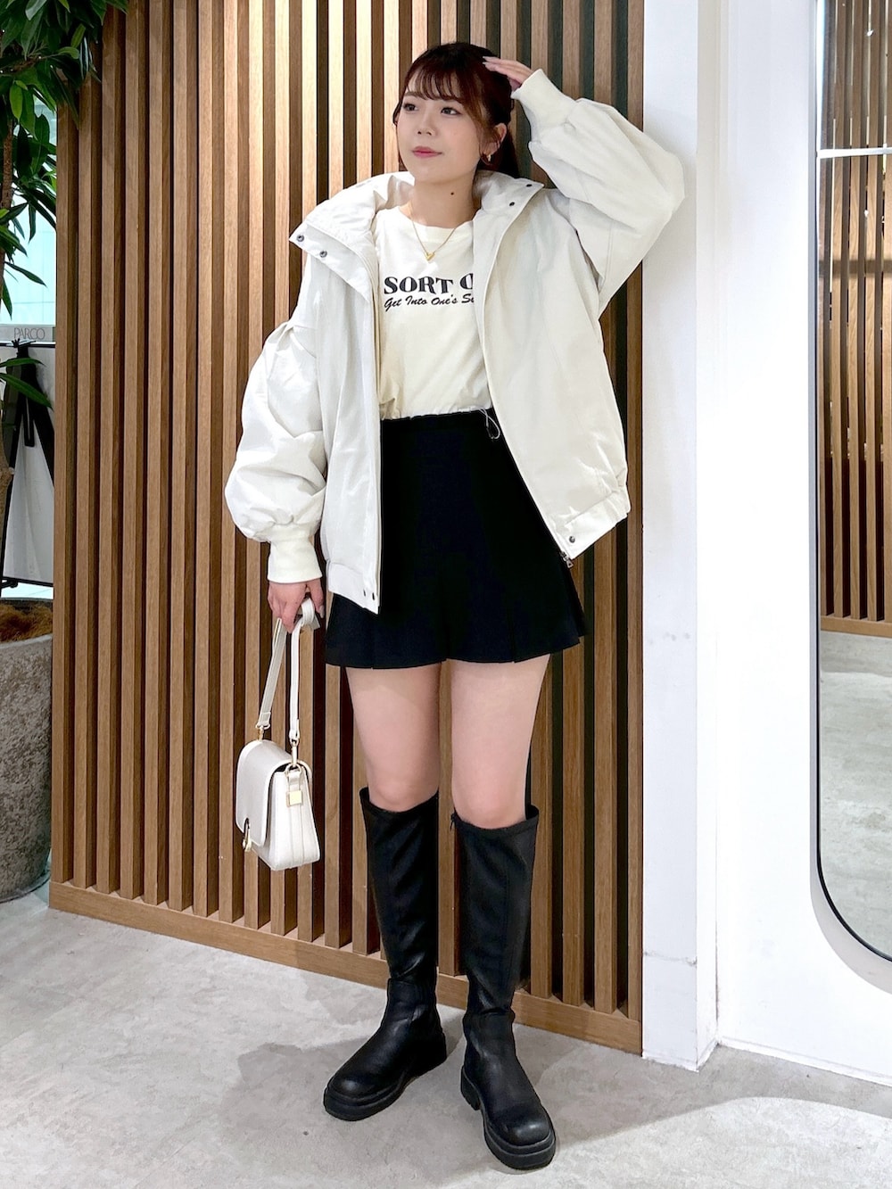 ホワイト系のブルゾン、ベージュ系のTシャツ/カットソー、ホワイト系のショルダーバッグを着用したレディースの冬コーディネートの2枚目の写真