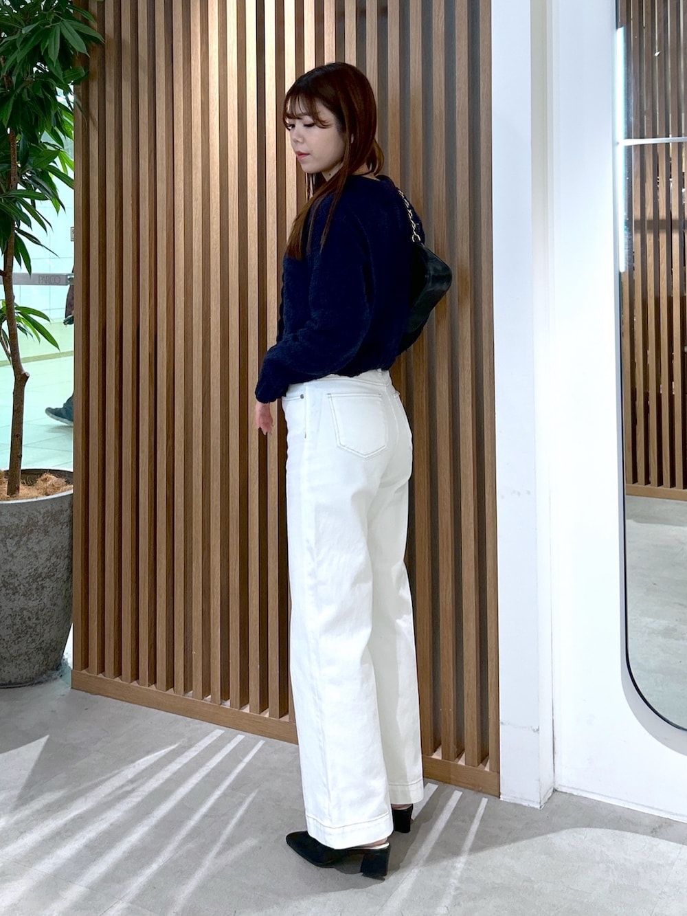 ブルー系のカーディガン/ボレロ、ブラック系のトートバッグ、ホワイト系のデニムパンツを着用したレディースの冬コーディネートの3枚目の写真