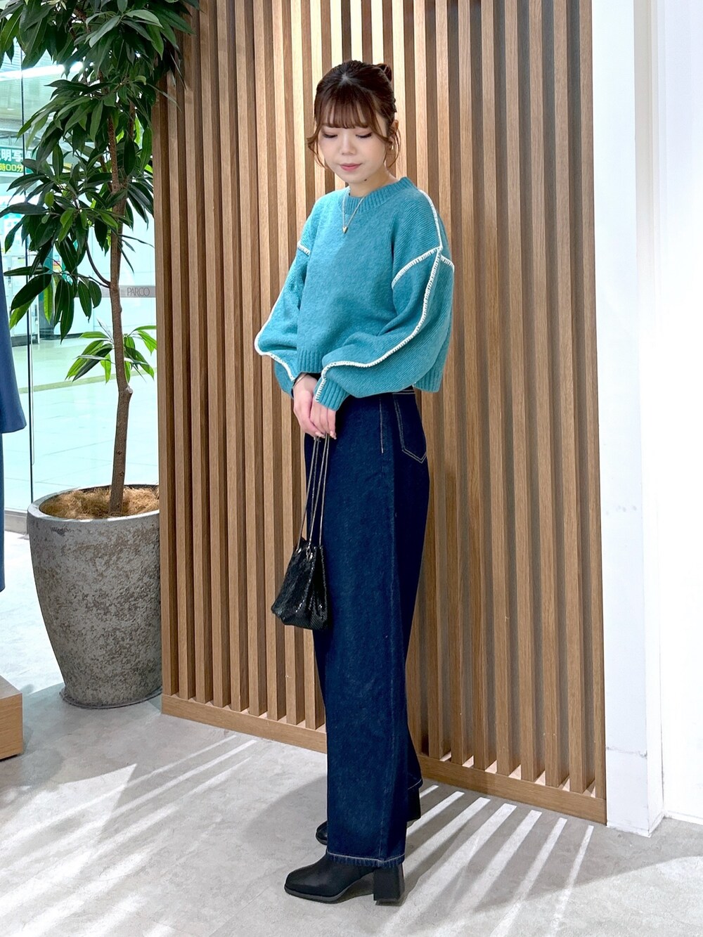 グリーン系のニット/セーター、ブルー系のデニムパンツ、ブラック系のショルダーバッグを着用したレディースの冬コーディネートの3枚目の写真