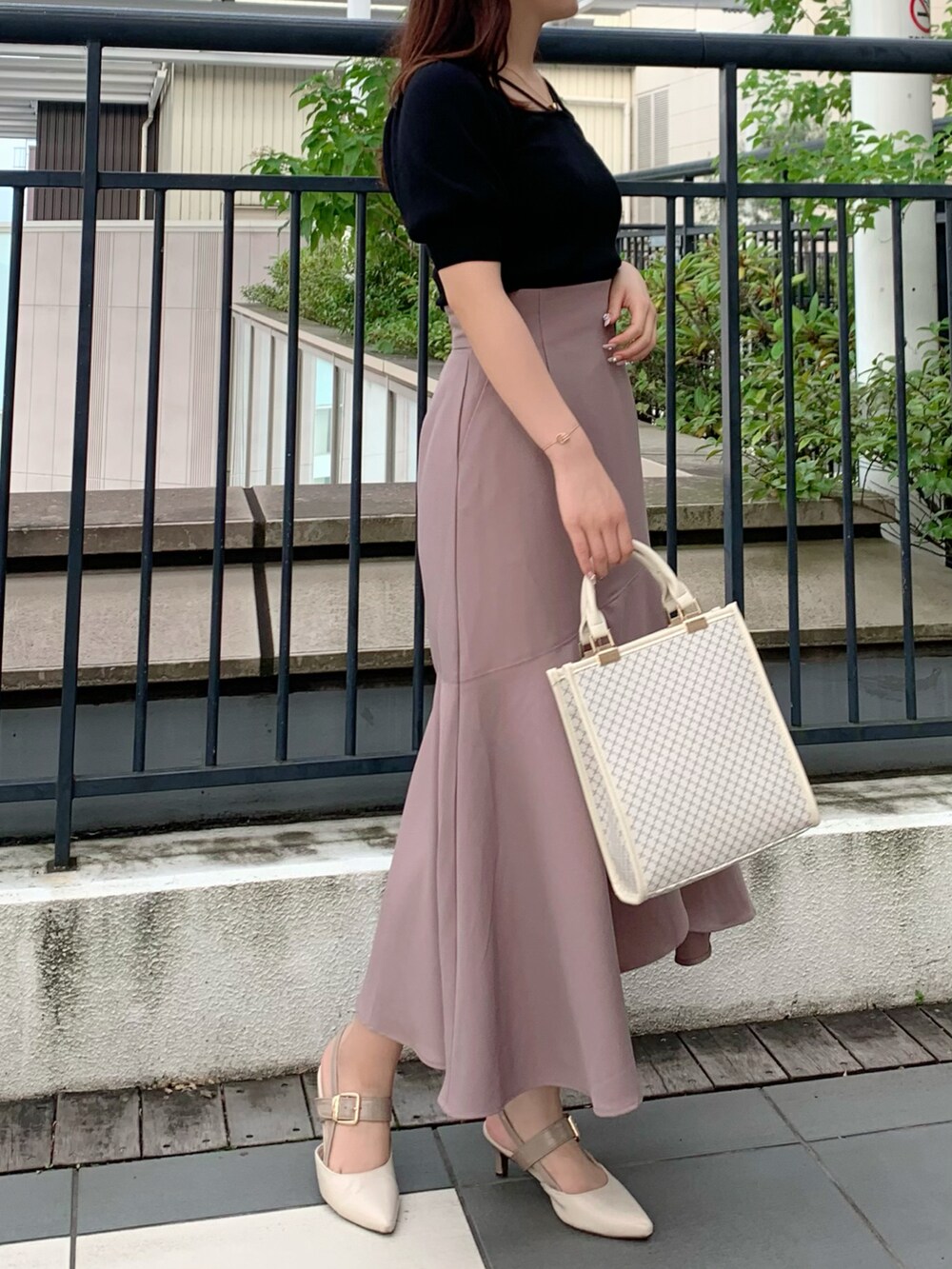 ブラック系のニット/セーター、ホワイト系のハンドバッグ、ピンク系のスカートを着用したレディースの夏コーディネートの2枚目の写真