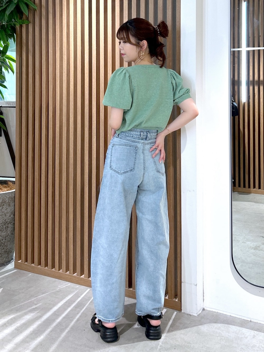 グリーン系のカーディガン/ボレロ、ホワイト系のキャミソール、ブルー系のデニムパンツを着用したレディースの春コーディネートの4枚目の写真