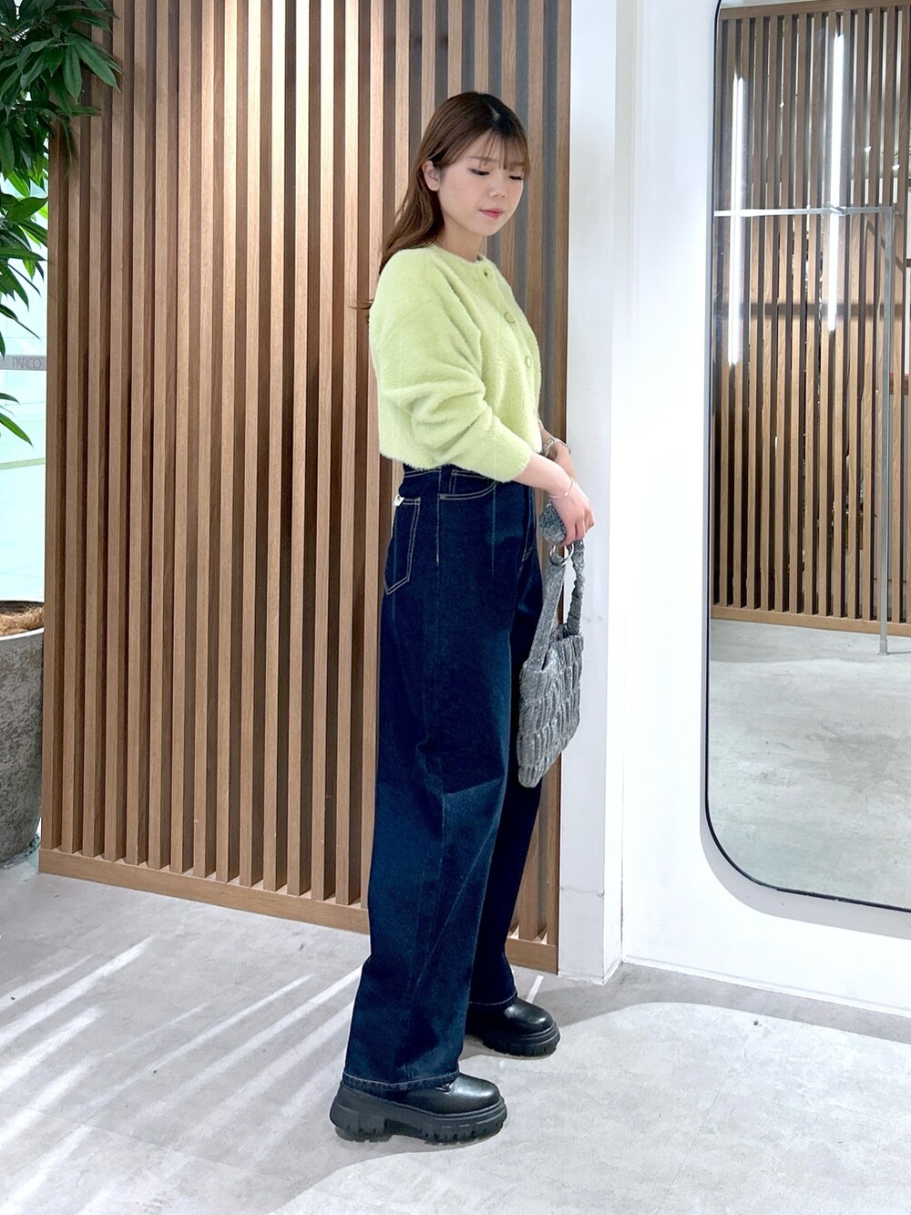 グリーン系のカーディガン/ボレロ、シルバー系のショルダーバッグ、ブルー系のデニムパンツを着用したレディースの冬コーディネートの2枚目の写真