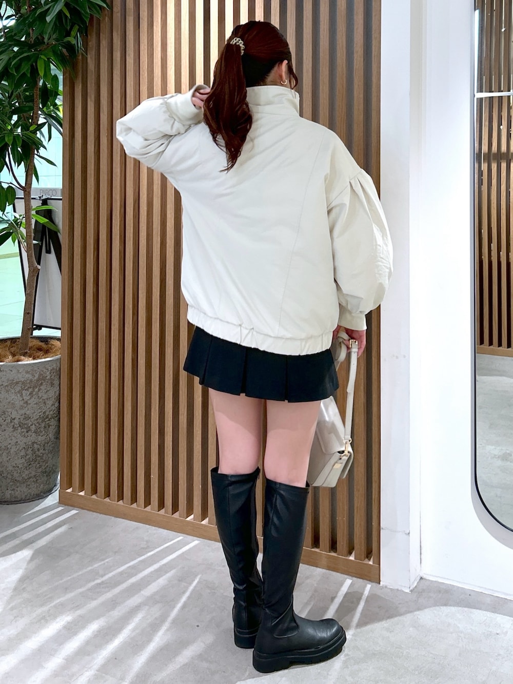 ホワイト系のブルゾン、ベージュ系のTシャツ/カットソー、ホワイト系のショルダーバッグを着用したレディースの冬コーディネートの4枚目の写真