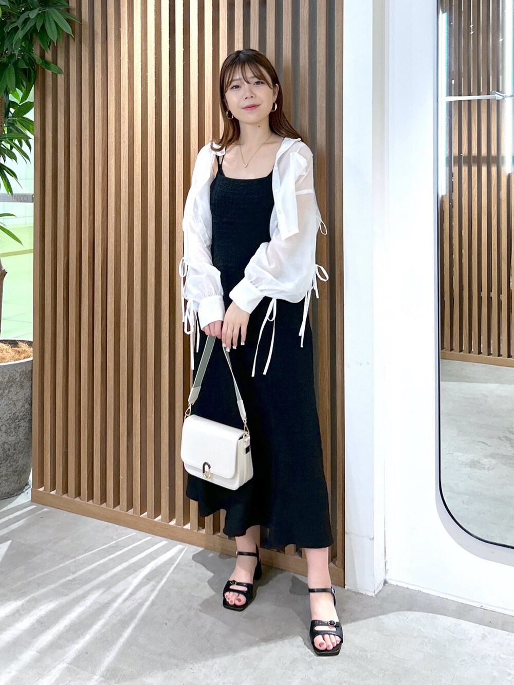ブラック系のワンピース、ホワイト系のショルダーバッグ、ブラック系のキャミソールを着用したレディースの夏コーディネートの2枚目の写真