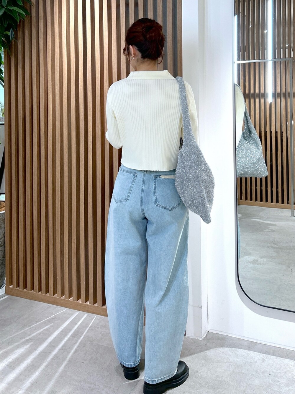 ホワイト系のニット/セーター、シルバー系のトートバッグ、ブルー系のデニムパンツを着用したレディースの冬コーディネートの4枚目の写真