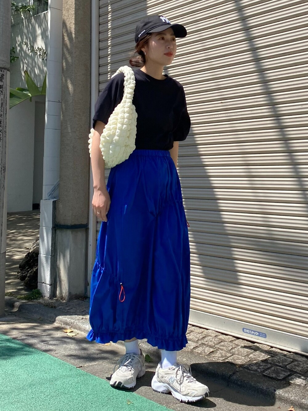 ブルー系のスカート、ブラック系のキャップを着用したレディースの春コーディネートの3枚目の写真