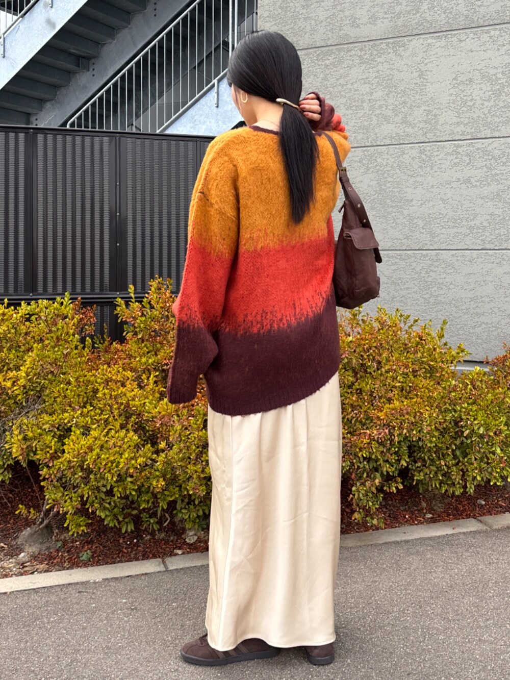 オレンジ系のカーディガン/ボレロ、ホワイト系のスカート、ブラウン系のハンドバッグを着用したレディースの秋コーディネートの4枚目の写真