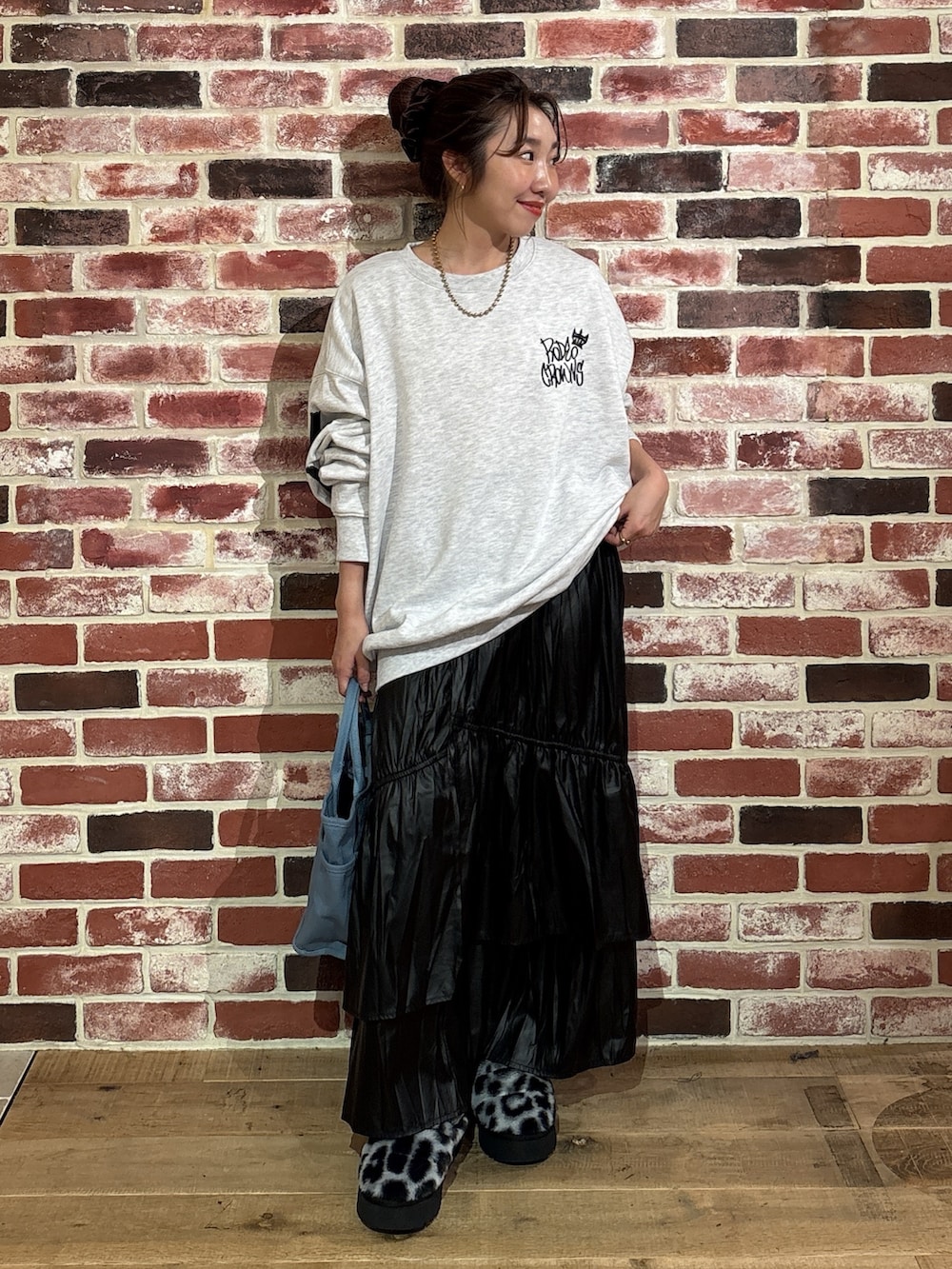 グレー系のスウェット、ブラック系のスカート、ブルー系のトートバッグを着用したレディースの秋コーディネートの3枚目の写真