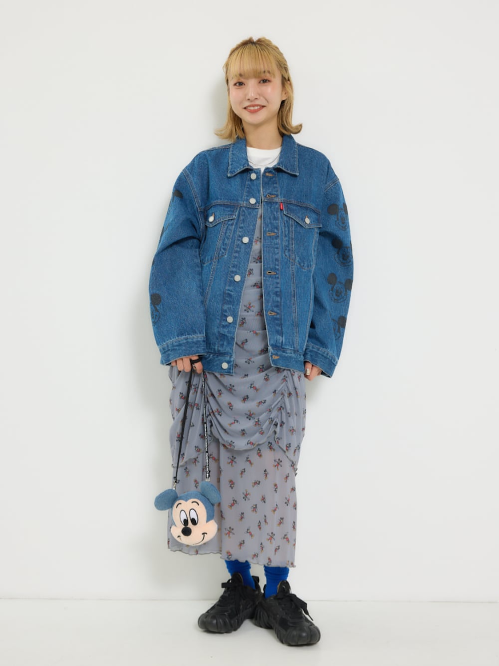 ブルー系のデニムジャケット、グレー系のワンピース、イエロー系のショルダーバッグを着用したレディースの冬コーディネートの2枚目の写真