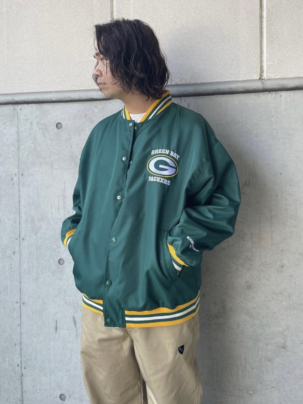 グリーン系のスタジャン、ベージュ系のチノパンツを着用したメンズの夏コーディネートの2枚目の写真