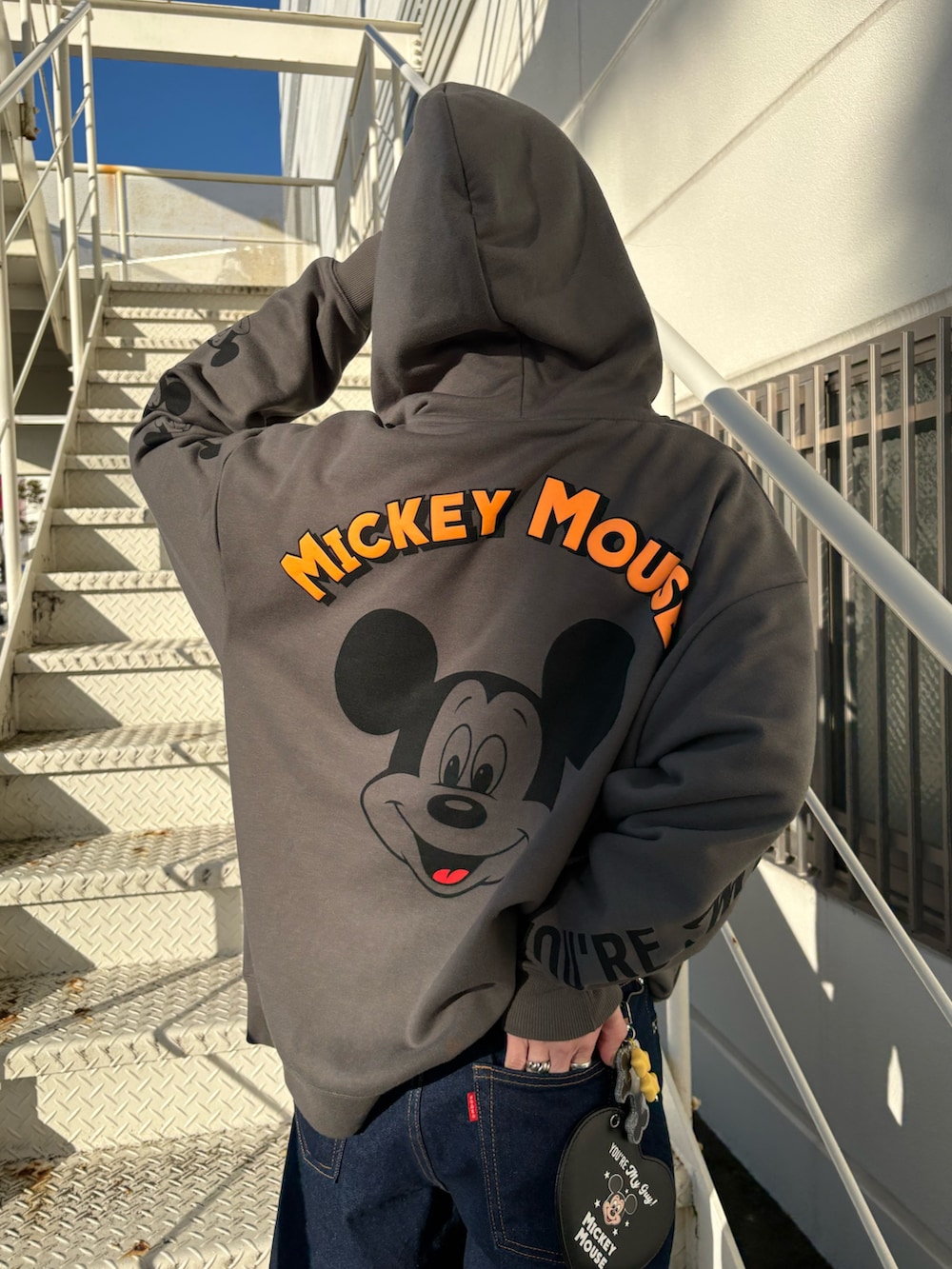 グレー系のパーカー、ブラック系のチャームを着用したレディースの冬コーディネートの2枚目の写真