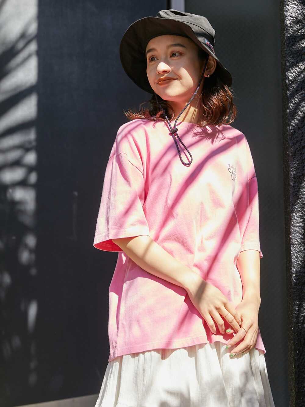 ピンク系のTシャツ/カットソー、ホワイト系のスカート、ブラック系のハットを着用したレディースの春コーディネートの3枚目の写真