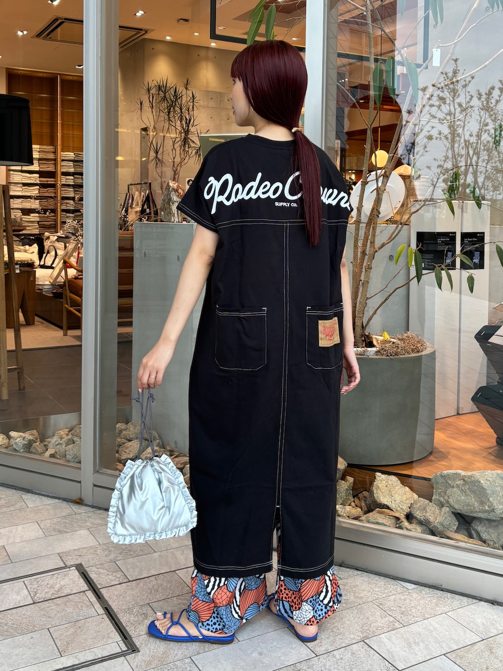 ブラック系のワンピース、オレンジ系のその他パンツ、ブルー系のサンダルを着用したレディースの春コーディネートの2枚目の写真