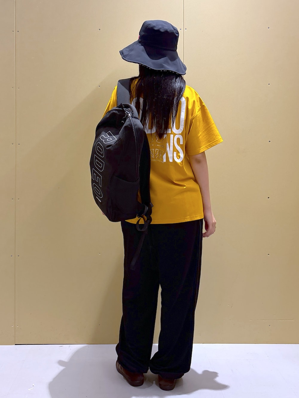 ブラック系のその他パンツ、イエロー系のTシャツ/カットソー、ブラック系のバックパック/リュックを着用したレディースの夏コーディネートの3枚目の写真