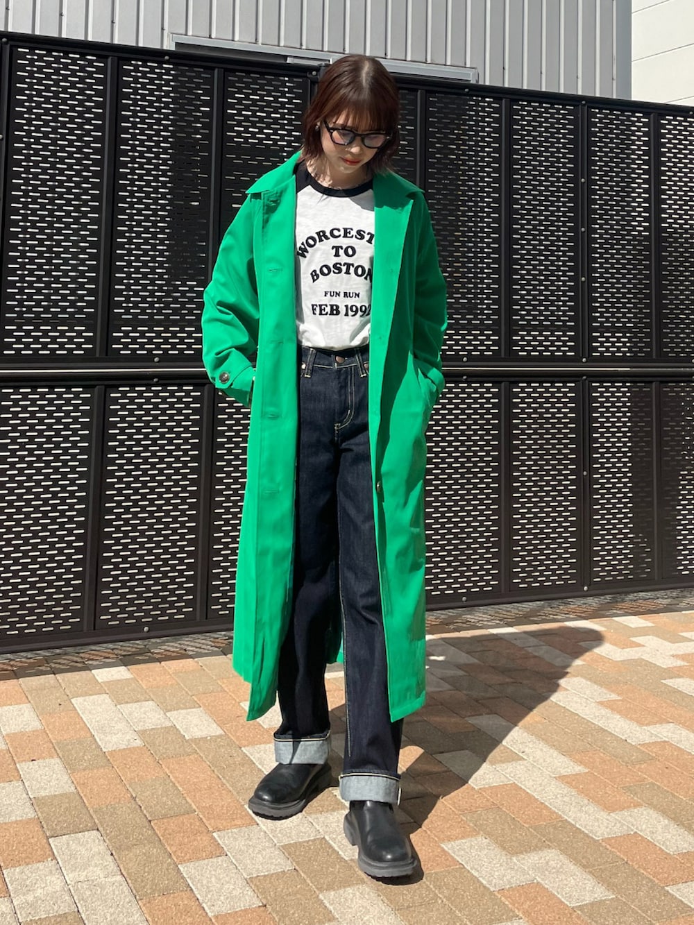 グリーン系のトレンチコートを着用したレディースの春コーディネートの2枚目の写真