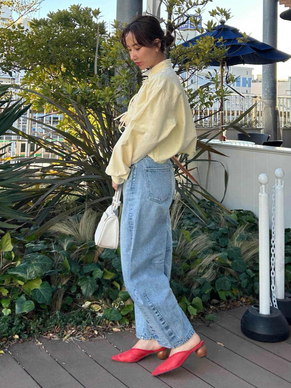イエロー系のシャツ/ブラウス、ブルー系のデニムパンツ、レッド系のサンダルを着用したレディースの春コーディネートの3枚目の写真