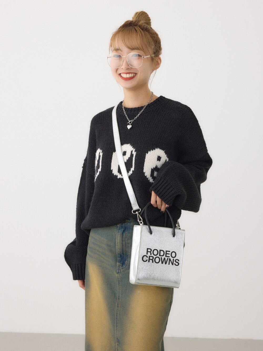 シルバー系のショルダーバッグ、ブラック系のニット/セーター、ブルー系のデニムスカートを着用したレディースの秋コーディネートの2枚目の写真