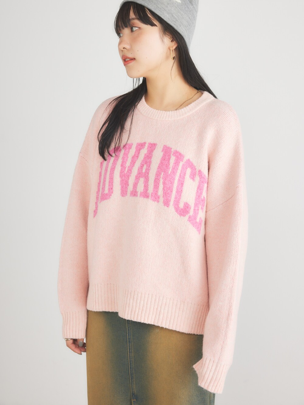 ピンク系のニット/セーター、ブルー系のデニムスカート、シルバー系のスニーカーを着用したレディースの冬コーディネートの3枚目の写真