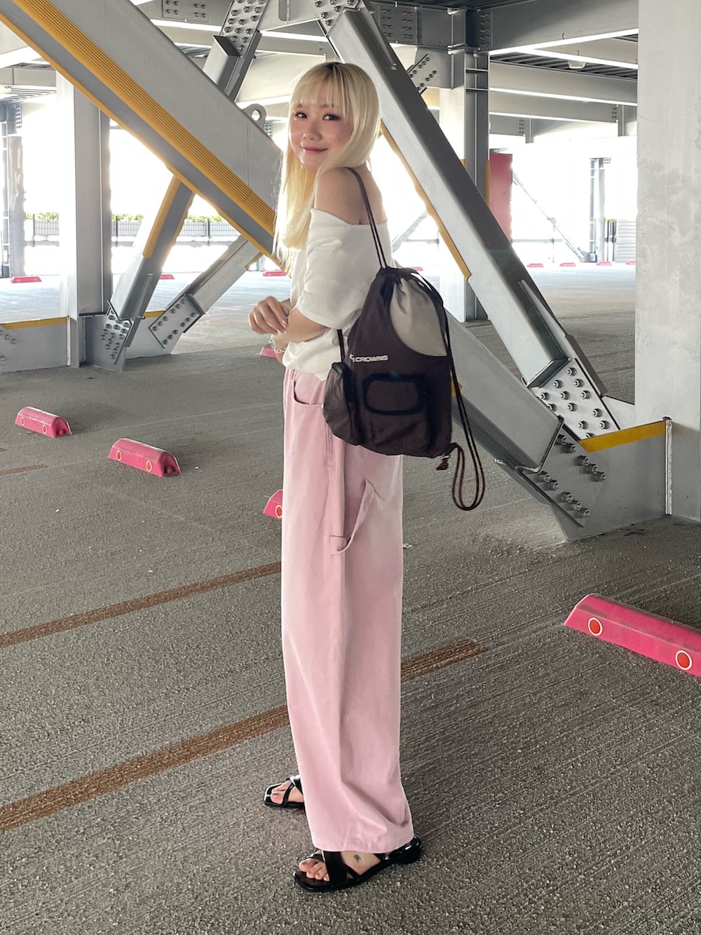 ピンク系のデニムパンツ、ホワイト系のTシャツ/カットソー、ブラウン系のバックパック/リュックを着用したレディースの夏コーディネートの3枚目の写真