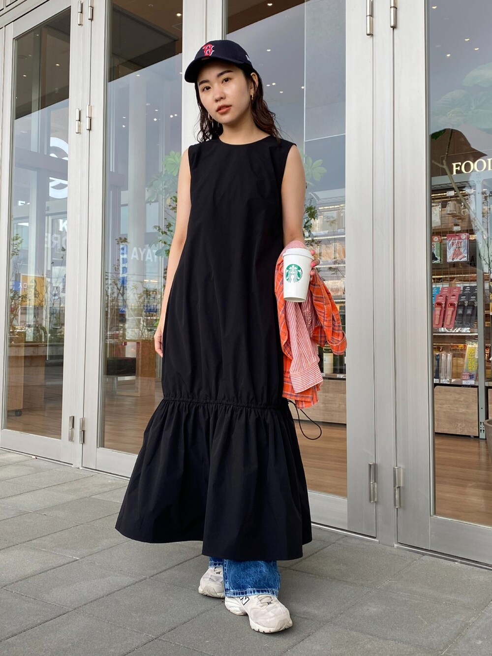 ブラック系のワンピース、ブルー系のキャップを着用したレディースの春コーディネートの2枚目の写真