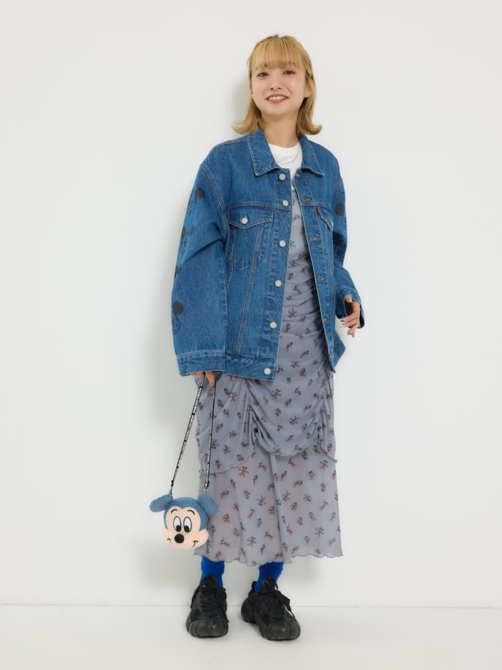 ブルー系のデニムジャケット、グレー系のワンピース、イエロー系のショルダーバッグを着用したレディースの冬コーディネートの5枚目の写真