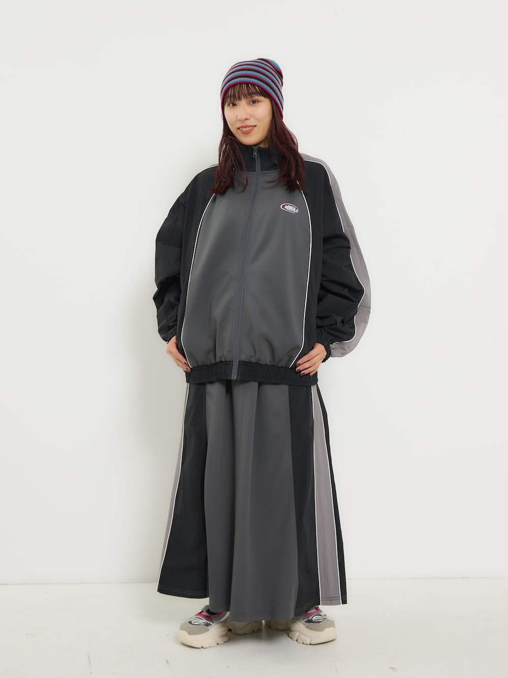 ブラック系のナイロンジャケット、ブラック系のスカート、シルバー系のスニーカーを着用したレディースの冬コーディネートの2枚目の写真