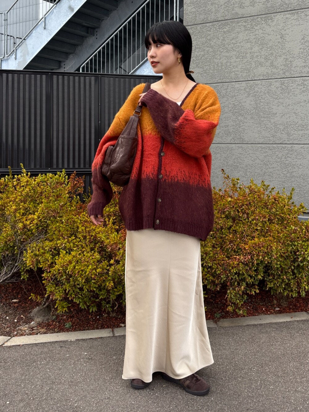 オレンジ系のカーディガン/ボレロ、ホワイト系のスカート、ブラウン系のハンドバッグを着用したレディースの秋コーディネートの3枚目の写真