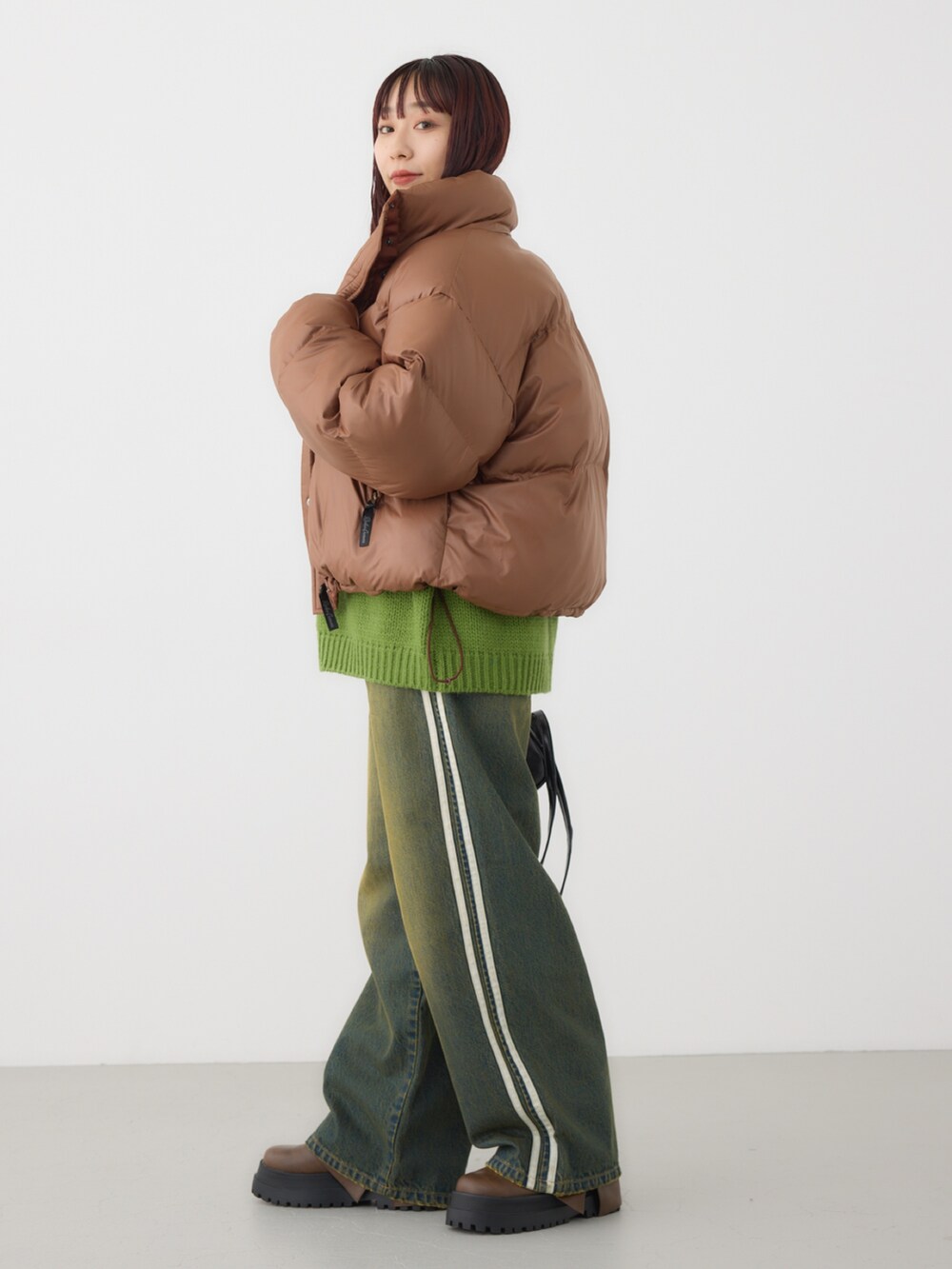 ブラウン系のダウンジャケット/コート、グリーン系のニット/セーター、ブラック系のショルダーバッグを着用したレディースの冬コーディネートの2枚目の写真