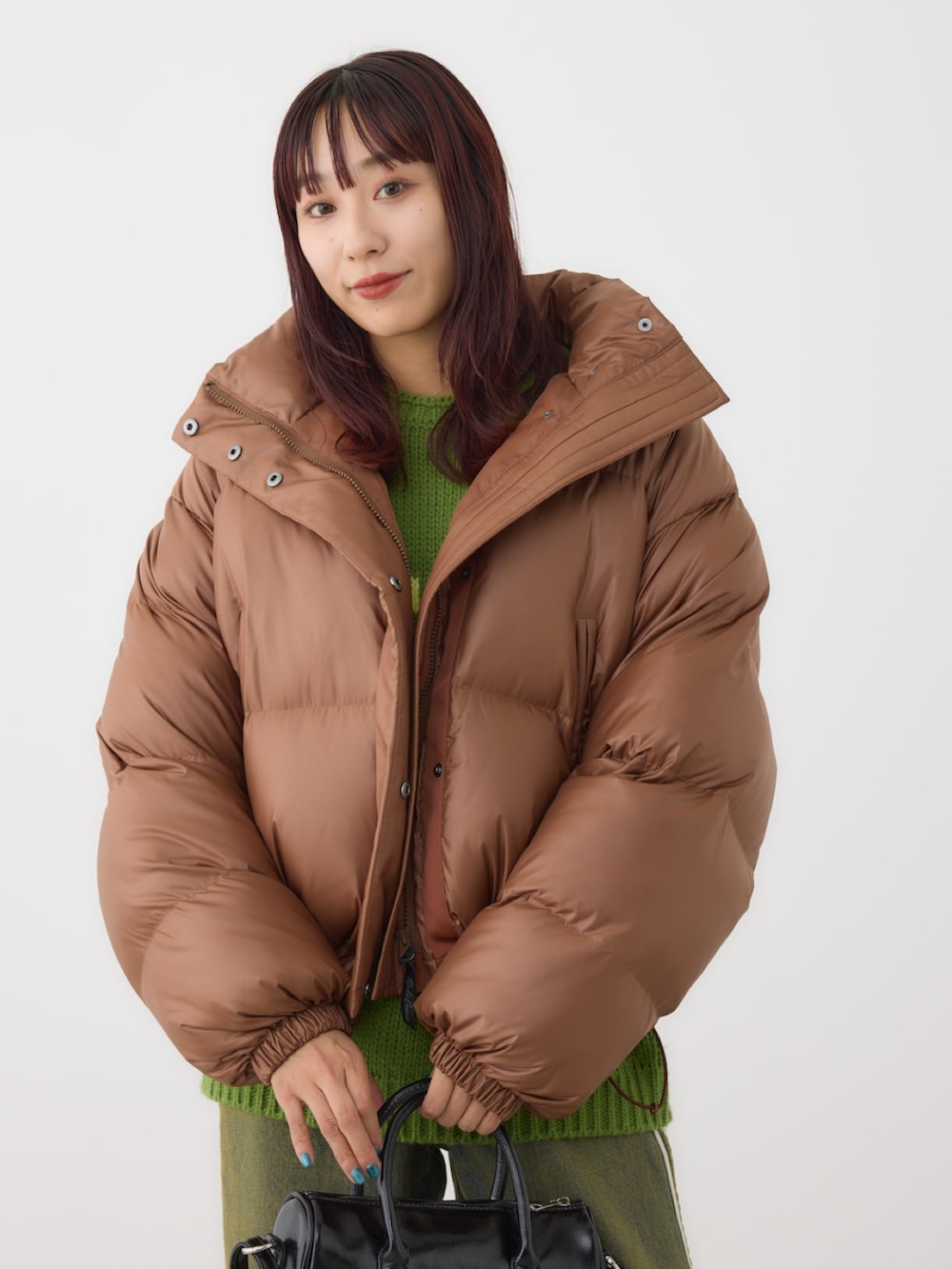 ブラウン系のダウンジャケット/コート、グリーン系のニット/セーター、ブラック系のショルダーバッグを着用したレディースの冬コーディネートの4枚目の写真