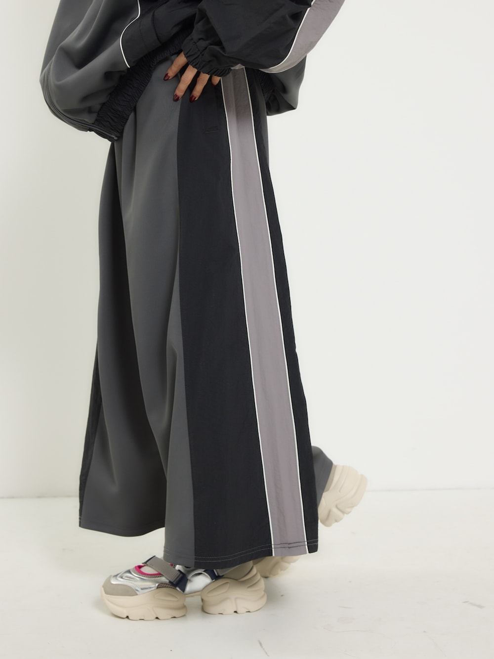 ブラック系のナイロンジャケット、ブラック系のスカート、シルバー系のスニーカーを着用したレディースの冬コーディネートの3枚目の写真