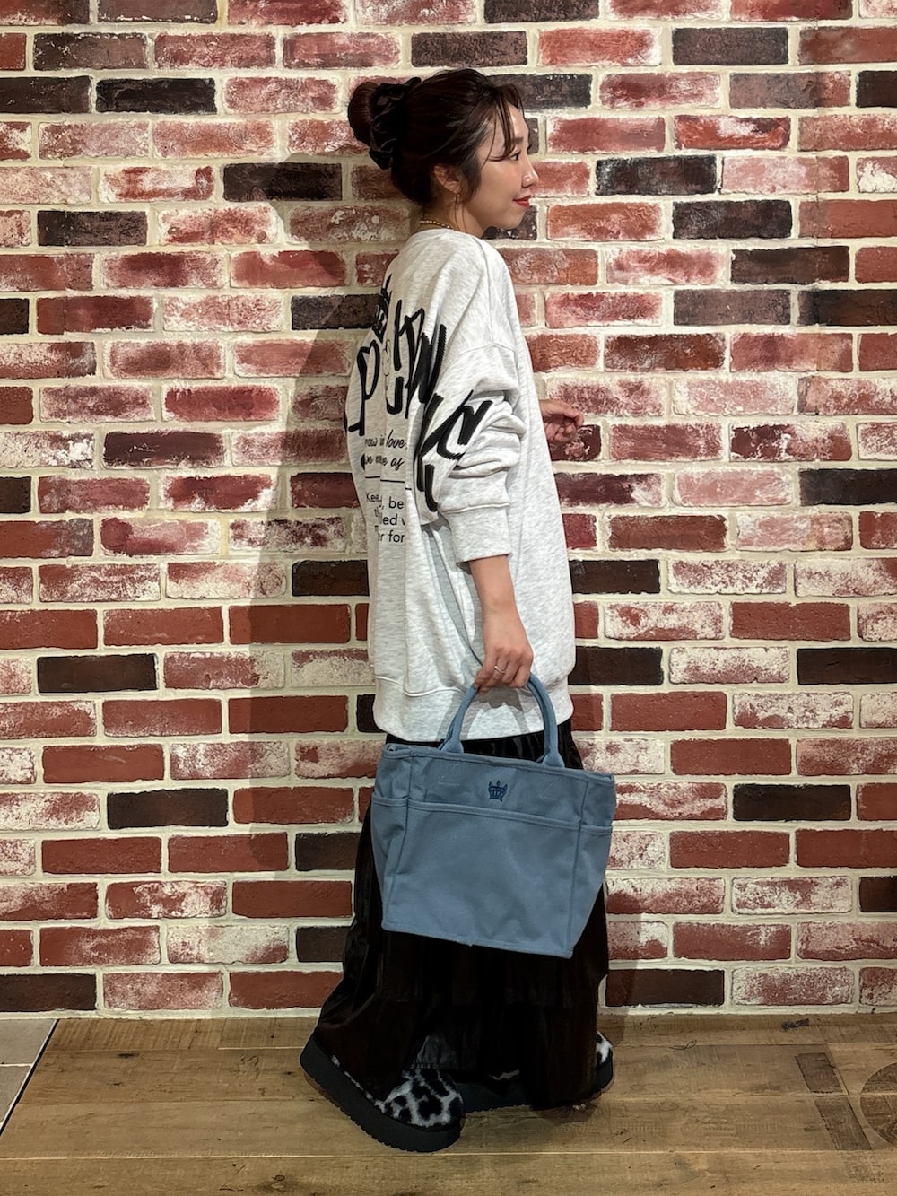 グレー系のスウェット、ブラック系のスカート、ブルー系のトートバッグを着用したレディースの秋コーディネートの2枚目の写真