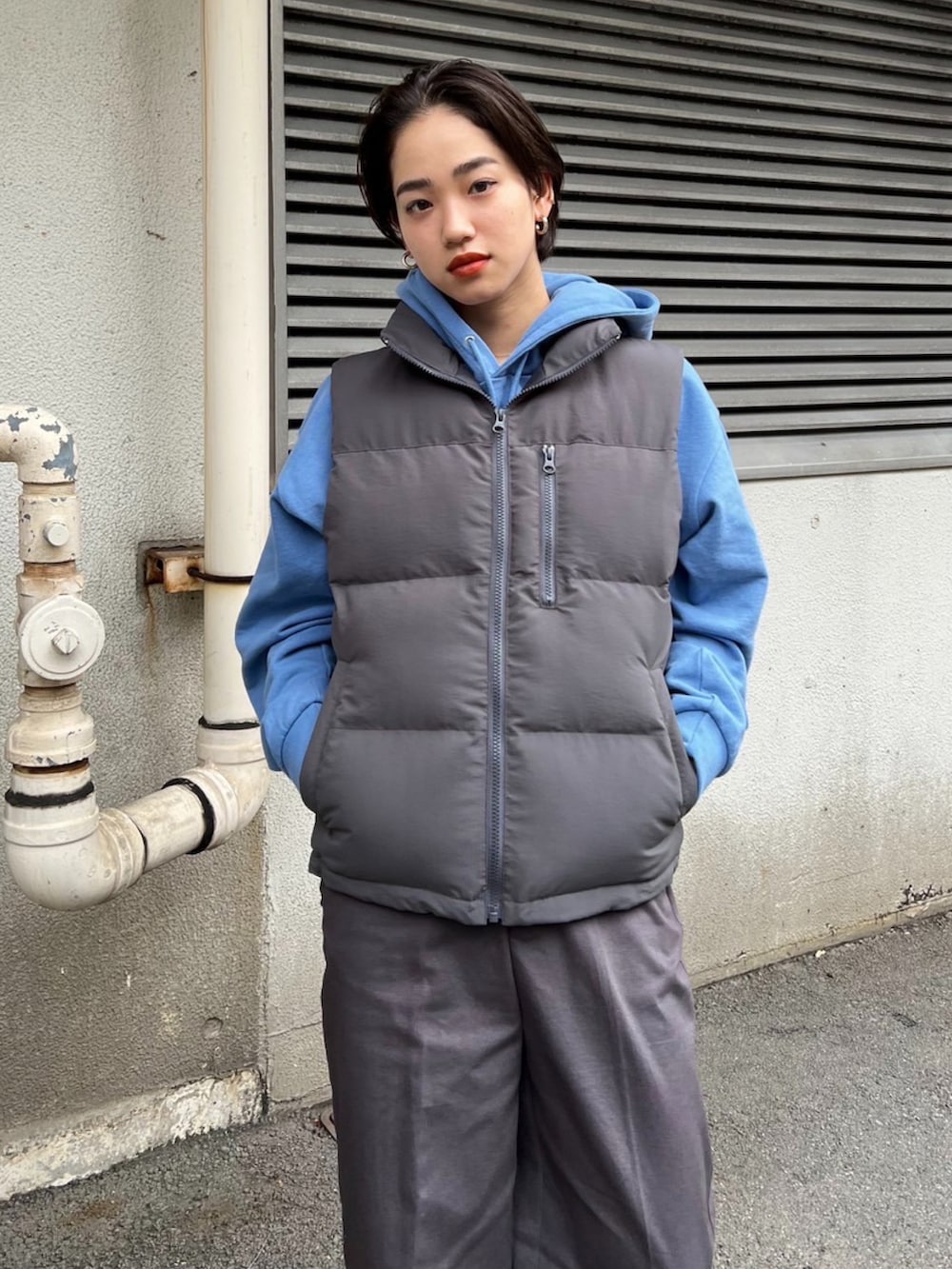グレー系のベスト、グレー系のその他パンツ、ブルー系のパーカーを着用したレディースの秋コーディネートの3枚目の写真