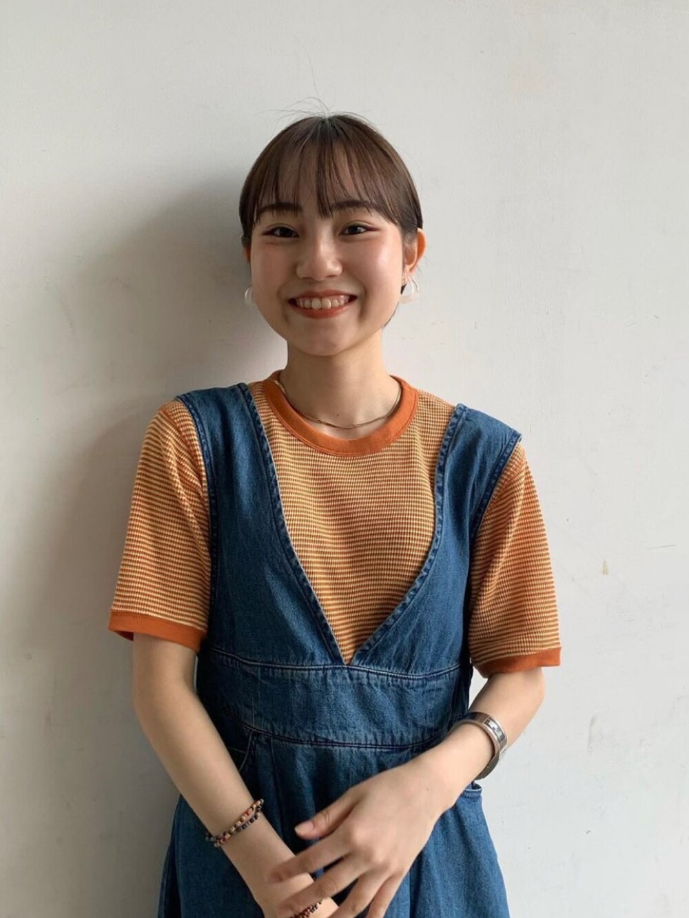 ブルー系のワンピース、オレンジ系のTシャツ/カットソーを着用したレディースの春コーディネートの2枚目の写真