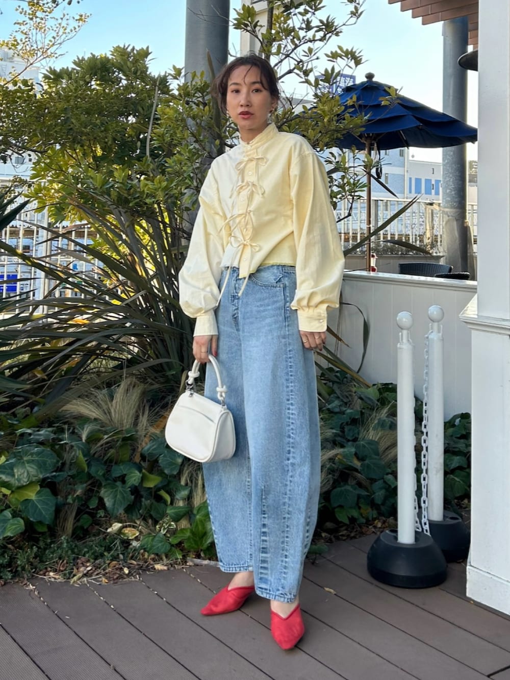 イエロー系のシャツ/ブラウス、ブルー系のデニムパンツ、レッド系のサンダルを着用したレディースの春コーディネートの2枚目の写真