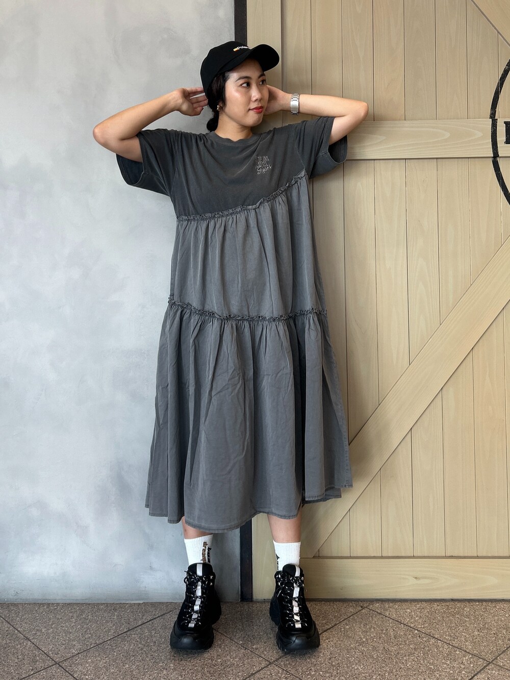 グリーン系のショルダーバッグ、ブラック系のワンピース、ブラック系のスニーカーを着用したレディースの夏コーディネートの2枚目の写真