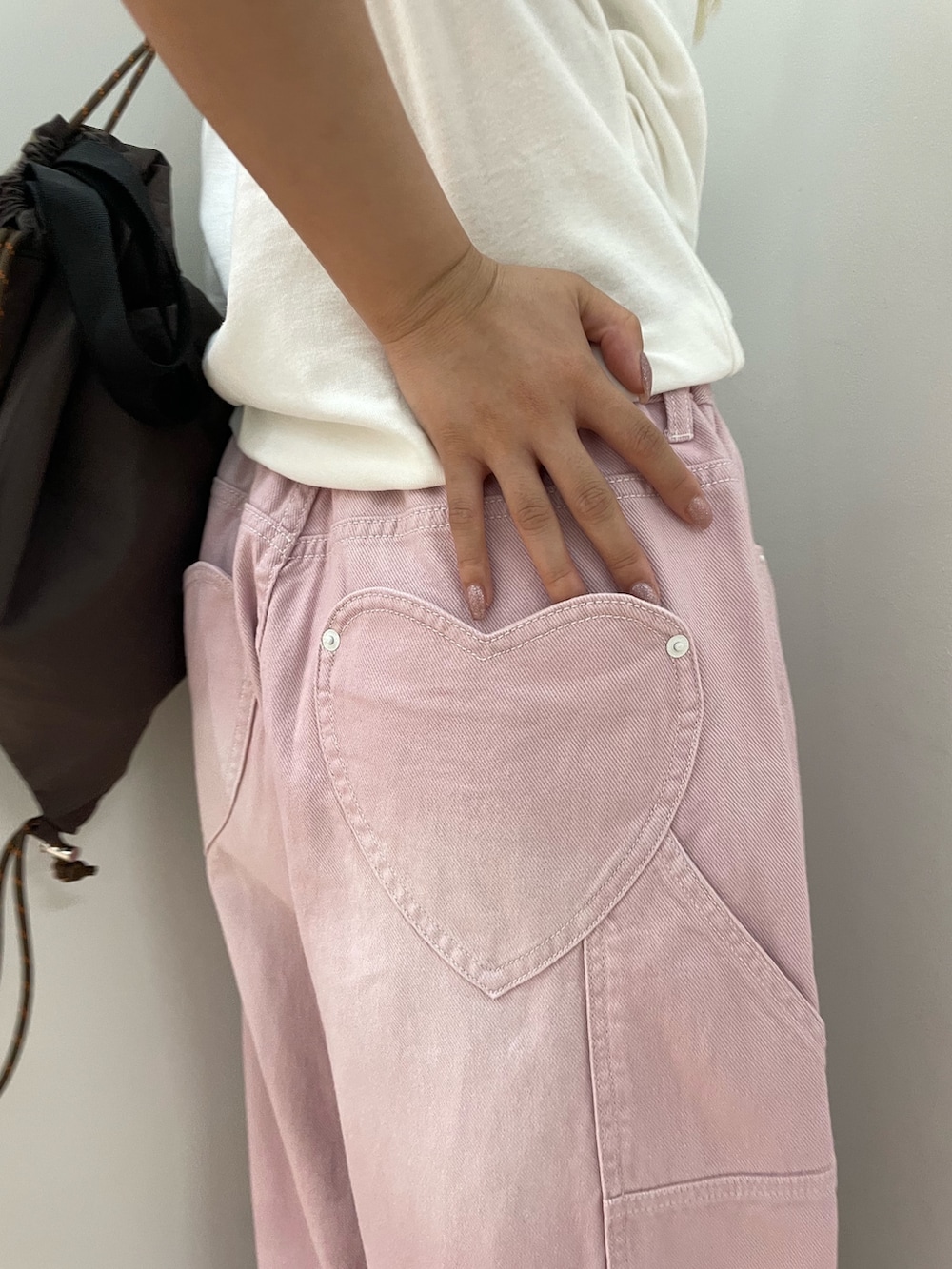 ピンク系のデニムパンツ、ホワイト系のTシャツ/カットソー、ブラウン系のバックパック/リュックを着用したレディースの夏コーディネートの4枚目の写真