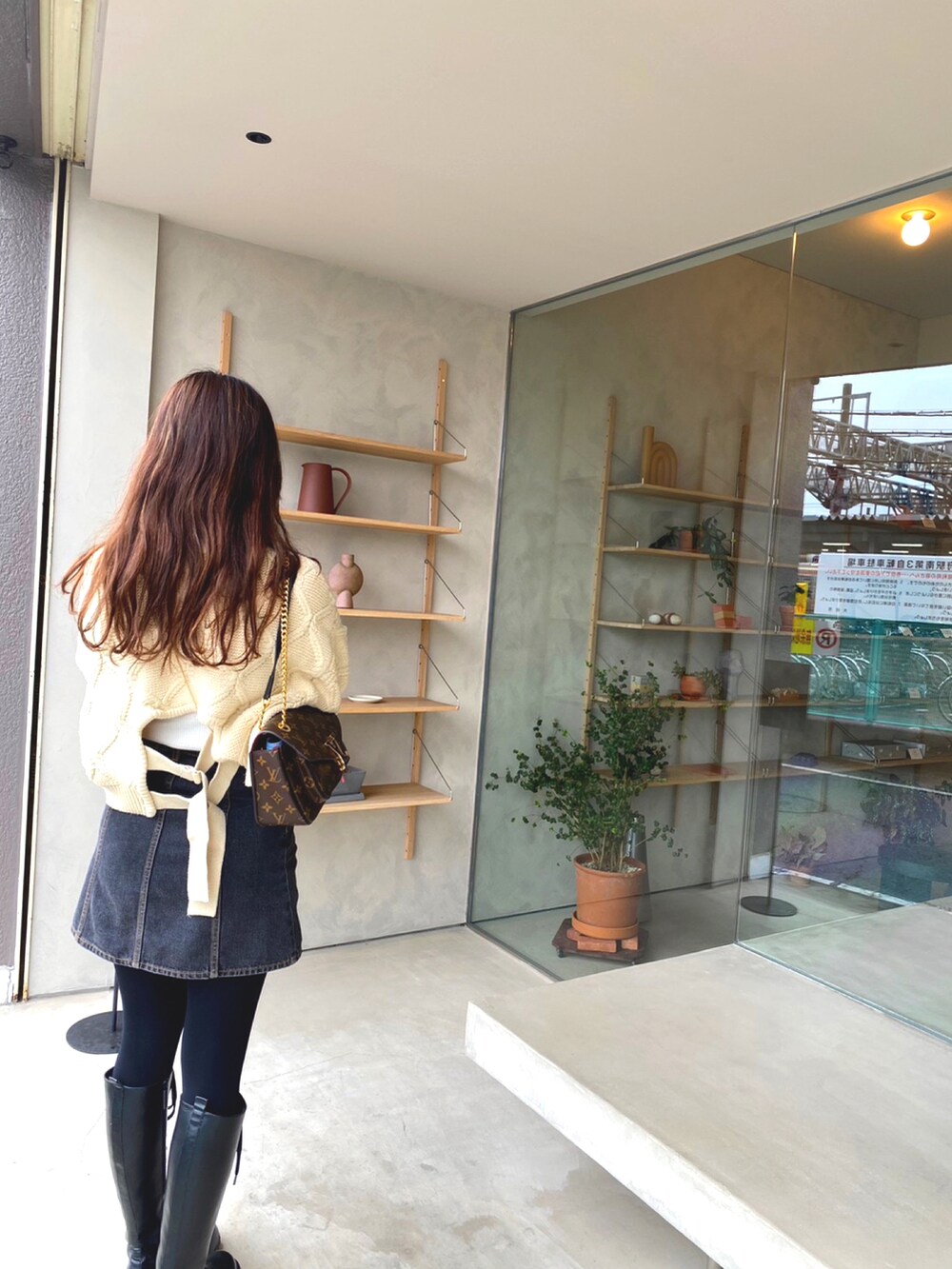 ホワイト系のニット/セーター、ブラウン系のバッグ、ブルー系のデニムスカートを着用したレディースの冬コーディネートの2枚目の写真